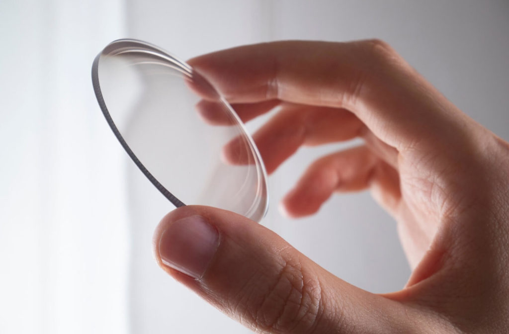 A hand holding up a lens for myopia control.