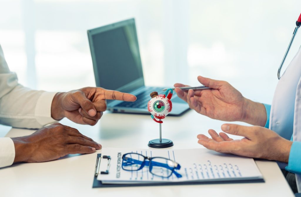 A close-up of a patient’s hands pointing to a 3D eye model during a discussion with their eye doctor.