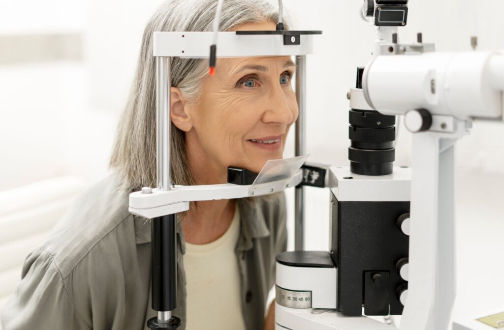 Older woman undergoing an eye exam with a slit lamp machine during a comprehensive eye exam at an optometrist’s office.