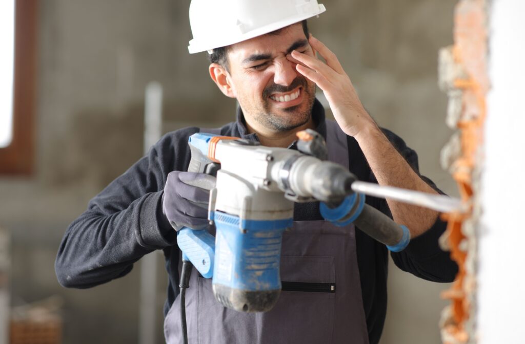 Construction worker holding left eye in pain after brick wall he was drilling shattered.