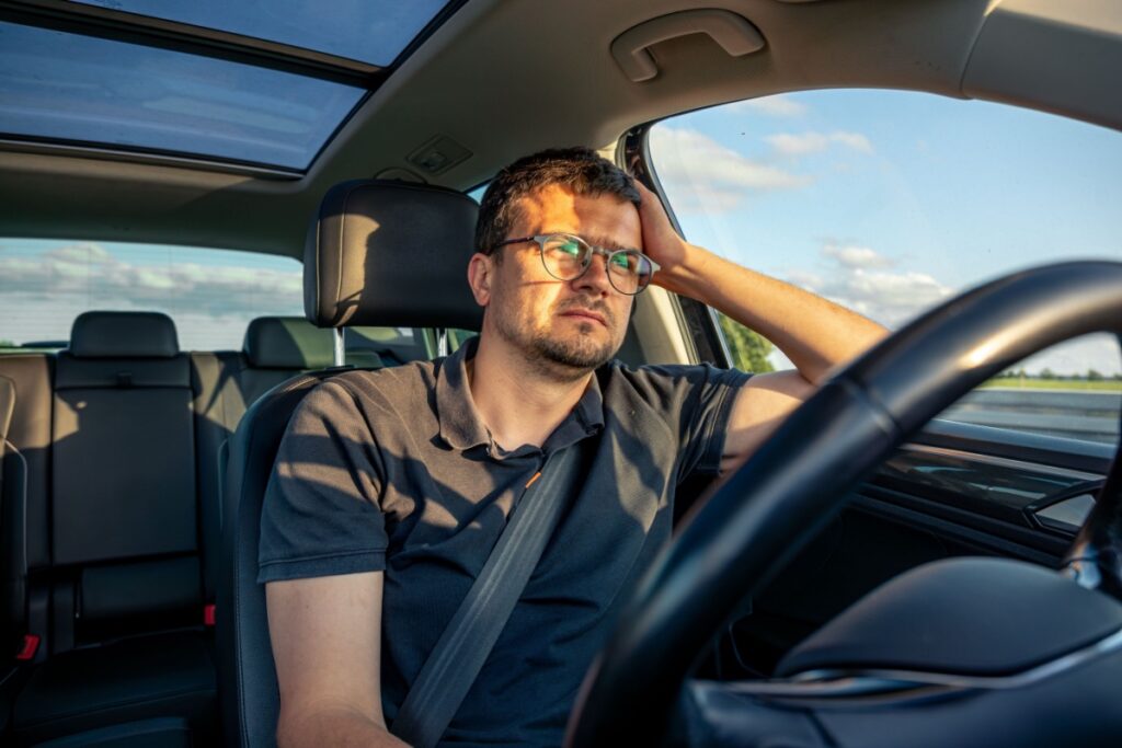 A man sitting in his car, stressed.