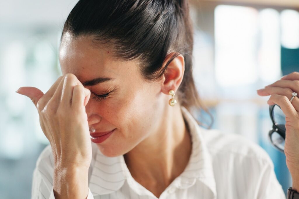 A person holding their hand up to their face due to vision problems caused by stress.