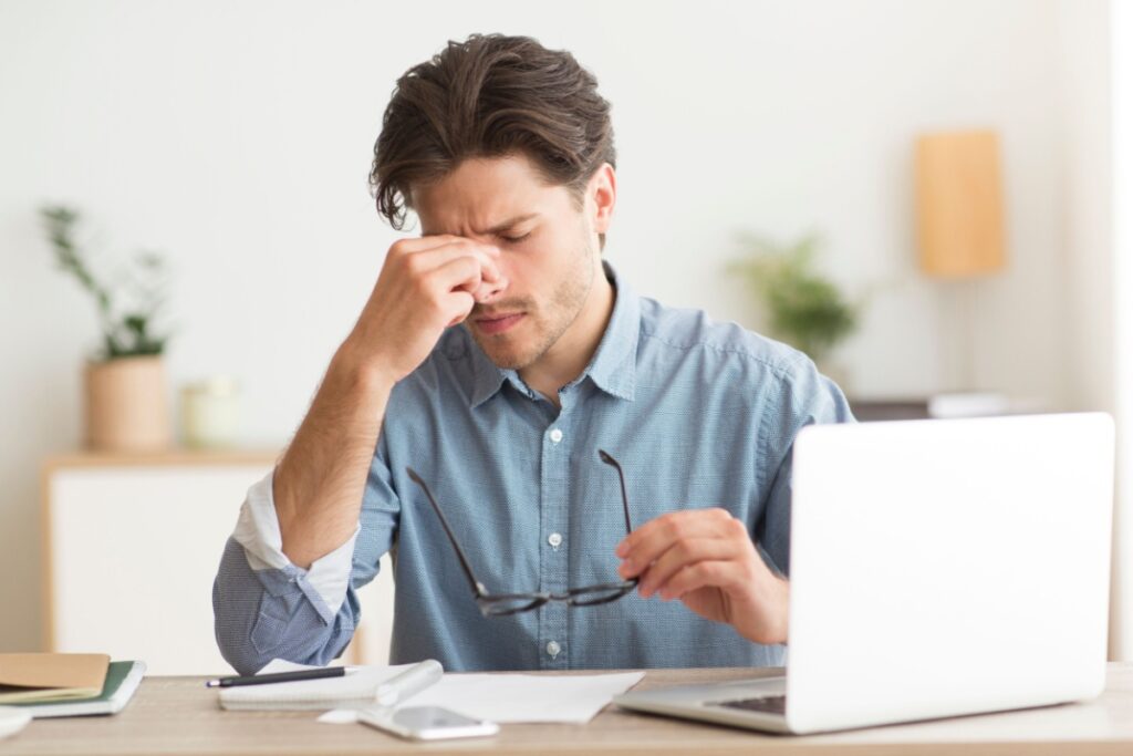 Man holding glasses rubbing his eyes